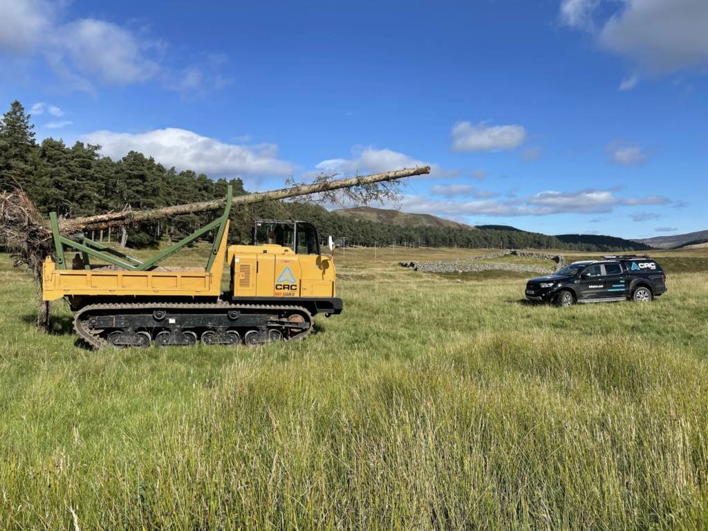 A CRC Dumper in the foreground transporting felled trees with a CRC branded vehicle in the background