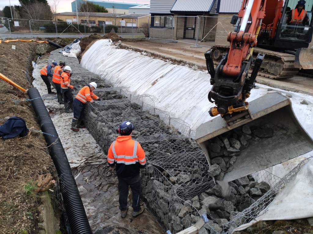CRC staff working on the gabion wall structure alongside an excavator
